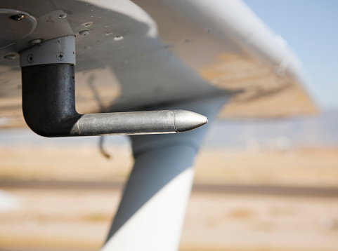 A close-up of the pitot tube on a small airplane's wing.