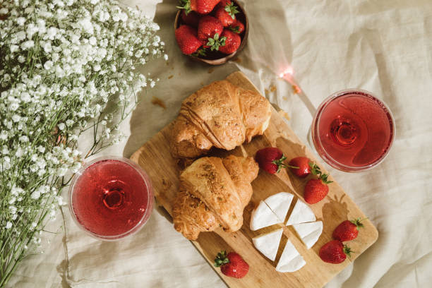 Cozy spring or summer picnic at home. Romantic picnic for Valentine's Day on February 14 with croissant, strawberries, cheese and rose champagne. Protea and gypsophila flower. stock photo