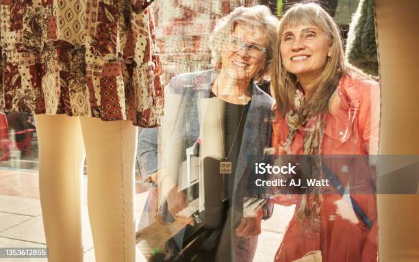 Two Mature Female Friends Smiling While Window Shopping Together Stock Photo - Download Image Now
