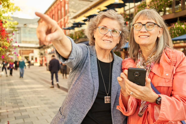 istock Smiling mature female friends using a smart phone while exploring the city 1353612881