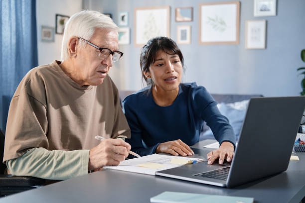 istock Senior man studying online with volunteer 1353613135