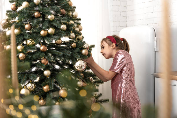 istock A little girl decorates a Christmas tree, hangs balls. 1353615757