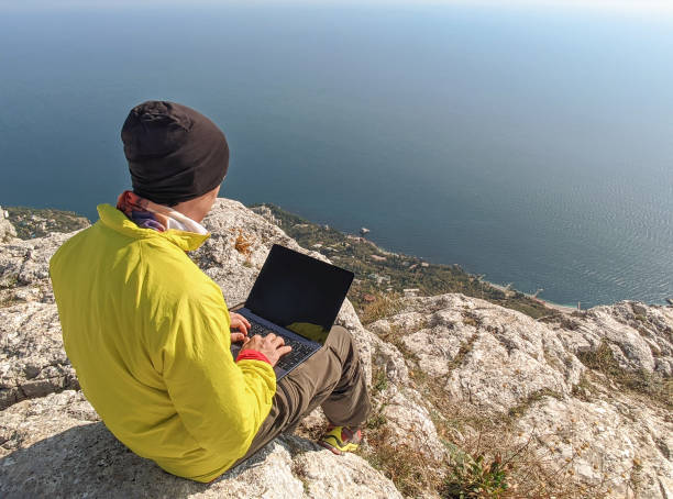man working on laptop on mountain - hipster people surfing the net internet imagens e fotografias de stock
