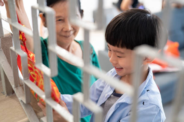 fröhlicher enkel, der seiner großmutter hilft, ihr haus zu dekorieren und sich darauf vorzubereiten, das chinesische neujahr zu feiern - 9 year old stock-fotos und bilder