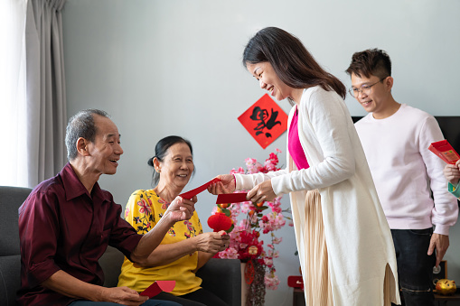 Daughter and son-in-law giving red packets Ang Pow to their grandparents during the Chinese New Year.