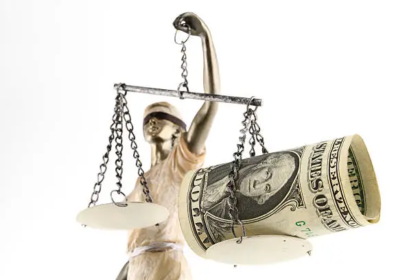 Justice (greek:themis,latin:justitia) blindfolded with scales, sword and money on one scale. Corruption and bribing concept.