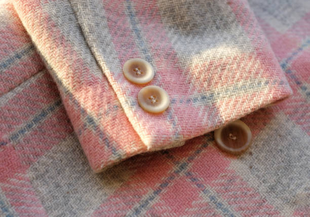 istock Buttons placed on a sleeve of fabric plaid wool jacket. Close up image. With sunlight 1353619061