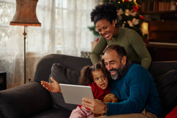istock Mixed race family gathered at home having fun using tablet 1353620210