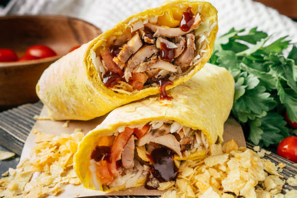 istock Crispy shawarma with chips, barbeque sauce, chicken in pita bread on wooden dark surface with cherry tomatoes, parsley 1353621493