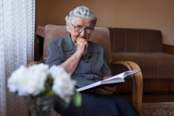 istock Concentration old woman reading a book at home 1353625270