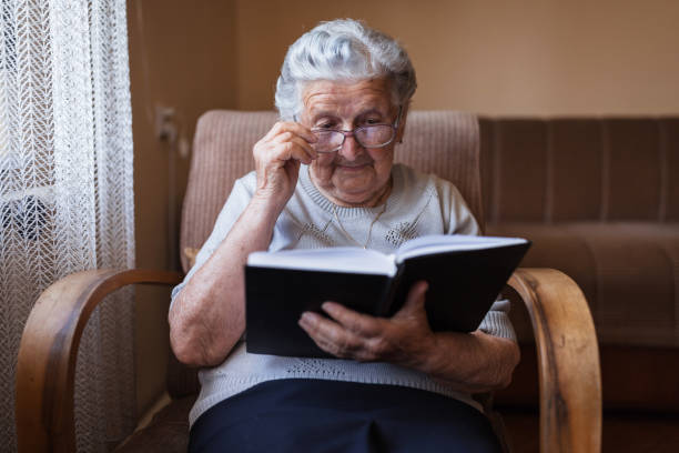 istock Elderly woman using eyeglasses when reading a book 1353625274