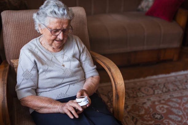 Grandmother sitting at home and using blood pressure Elderly lady using finger blood pressure monitor at home oxygen monitor stock pictures, royalty-free photos & images