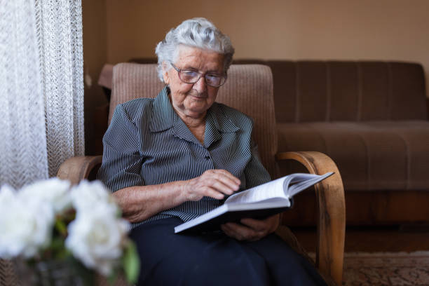 istock Concentration old woman reading a book at home 1353625297