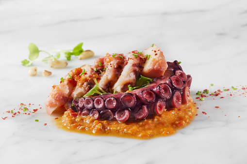 Tomato Braised Octopus with Romesco Sauce, Smoked Paprika, pine nuts and Mustard Greens