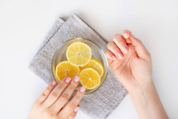 succo di limone, cosmetici naturali. la donna che immerge le unghie nell'acqua del succo di limone - water lime foto e immagini stock