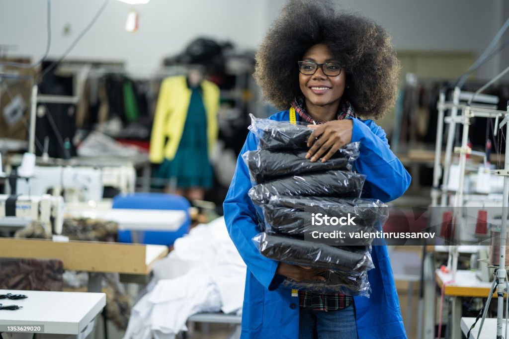 African American woman working at a textile factory,  carrying finished items for sell Garment Stock Photo