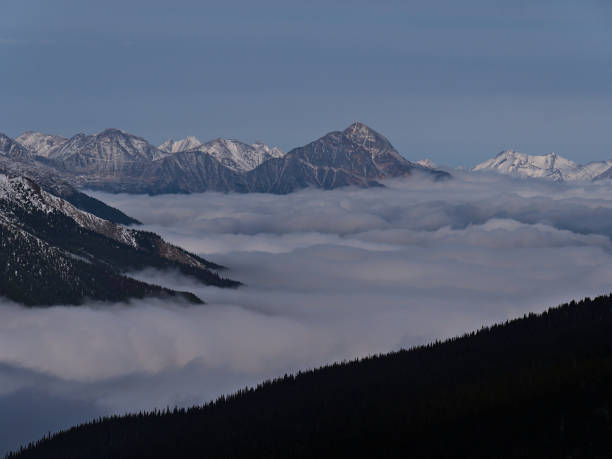 Stunning view of the Rocky Mountains near Jasper, Alberta, Canada with Pyramid Mountain above a sea of clouds and the silhouettes of coniferous forest. Stunning view of the Rocky Mountains near Jasper, Alberta, Canada with Pyramid Mountain above a sea of clouds and the silhouettes of coniferous forest in front in late autumn. low viewing point stock pictures, royalty-free photos & images