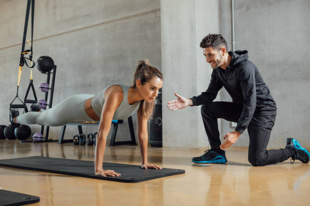 istock Personal trainer helps woman at gym. 1353631167