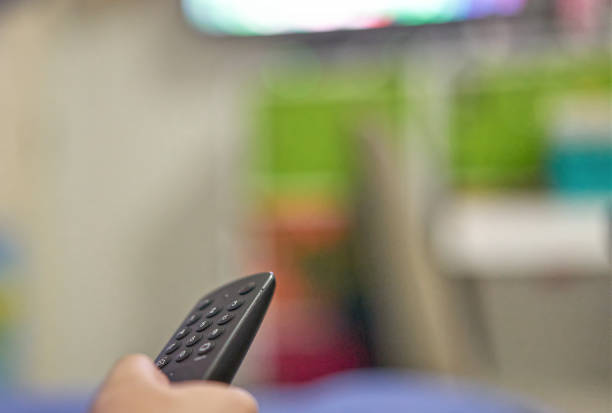 istock Hand use remote control tv for change channels in living room 1353631810