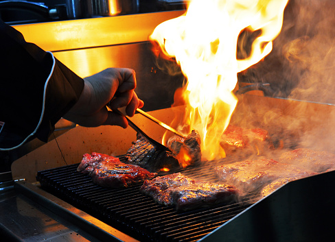 the chef prepares the meat on the grill. High quality photo