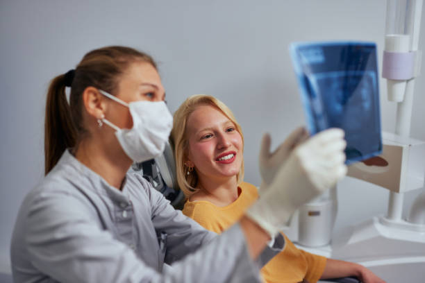 istock Young female dentist analyzing an x-ray with patient 1353632979