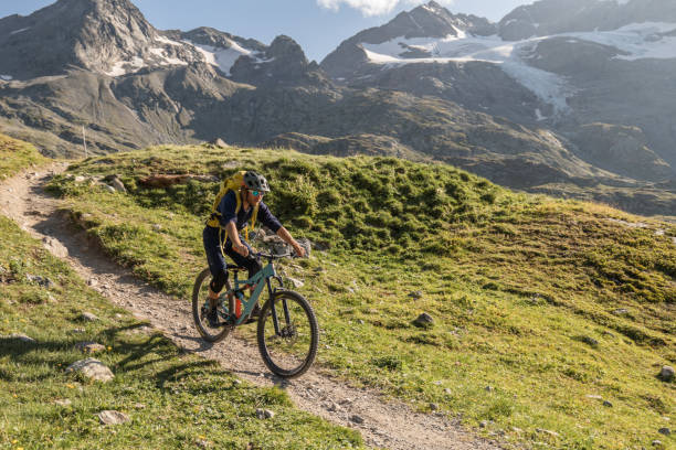 istock Mountain biker rides along alpine lake 1353633505