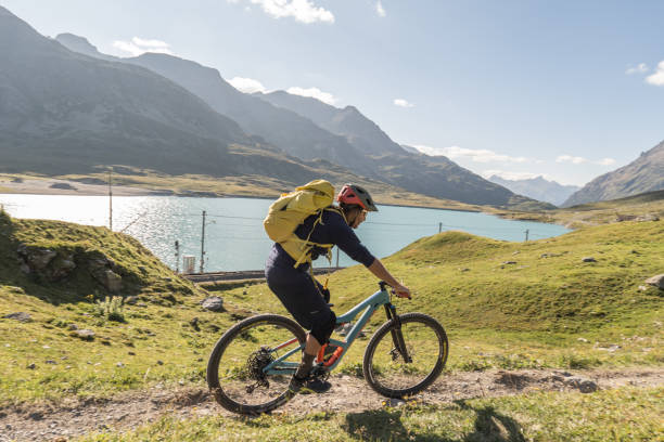 istock Mountain biker rides along alpine lake 1353634648