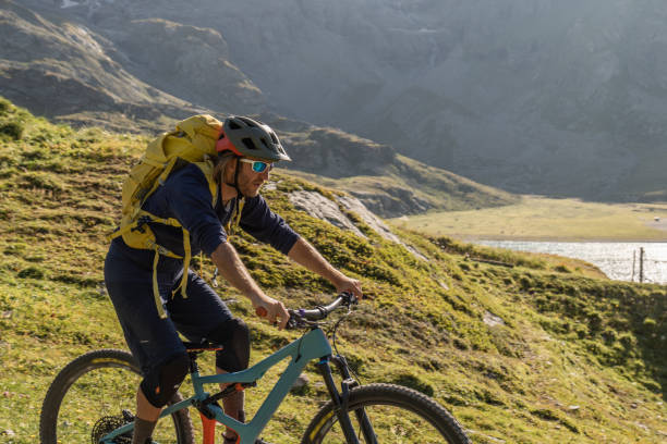 istock Mountain biker rides along alpine lake 1353635308