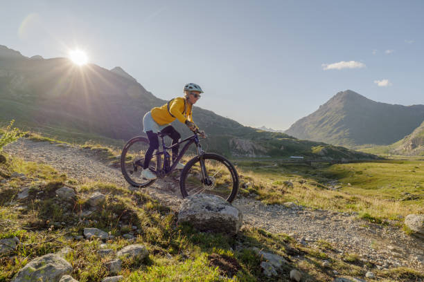 istock Woman mountain biker rides along alpine trail in Summer 1353635507