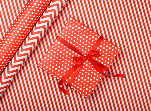 Close up packing and wrapping gifts with red and white paper, table top view, flat lay