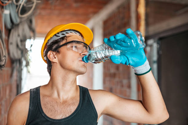 istock Caucasian worker wearing safety helmet is drinking water after finishing work 1353639733