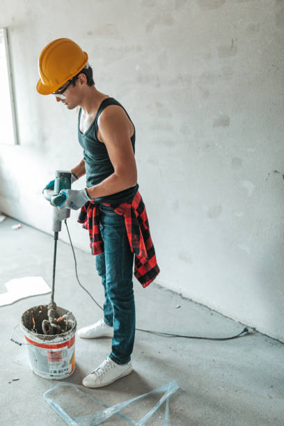 istock Cement mix tile adhesive in a bucket for tiling using an electric drill 1353639823