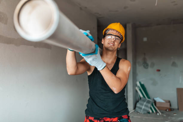 istock Young confident plumber preparing plastic pipes for installation in building under construction 1353639824