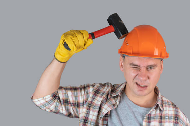 istock A worker in an orange hardhat hits a helmet with a hammer, protective workwear in industry, copyspace 1353640606