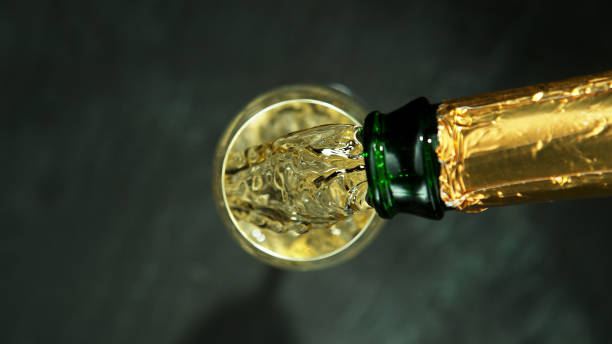 top shot of pouring champagne wine into glass. - champagne champagne flute pouring wine imagens e fotografias de stock