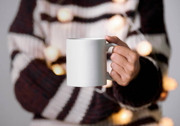 istock women hand holding white ceramic coffee cup with light decoration. mockup mug for creative advertising text message content. 1353646388