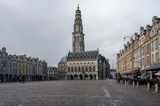 Arras, France - November 4, 2021: Town square of Arras, France. UNESCO World Heritage Site, the Belfry of Arras, against a dark grey sky