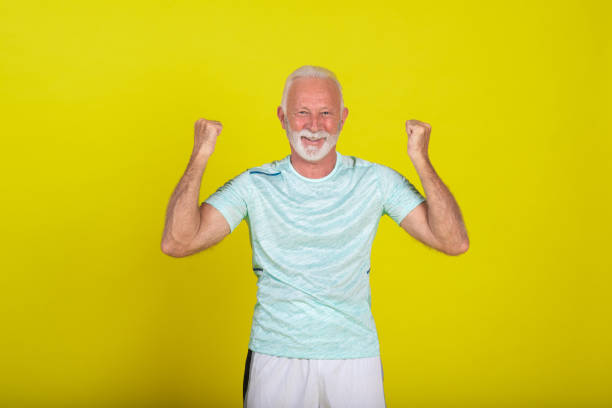 Studio portrait of a senior man in sports clothing showing a bicep.