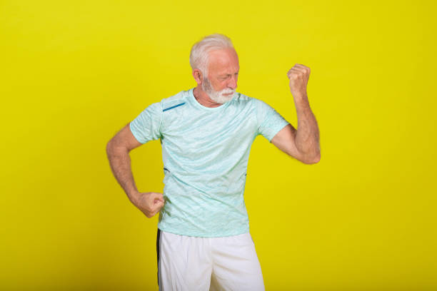 Studio portrait of a senior man in sports clothing showing a bicep.