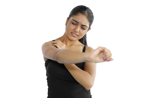 Young woman in casual wear experiencing shoulder pain.
