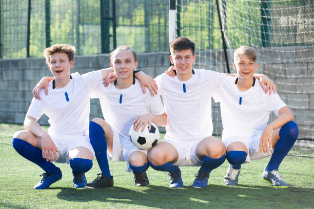 jeunes joueurs de football assis sur le terrain - milieu de terrain photos et images de collection