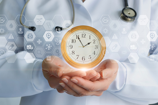 Doctor maintains a clock on a blurred background.