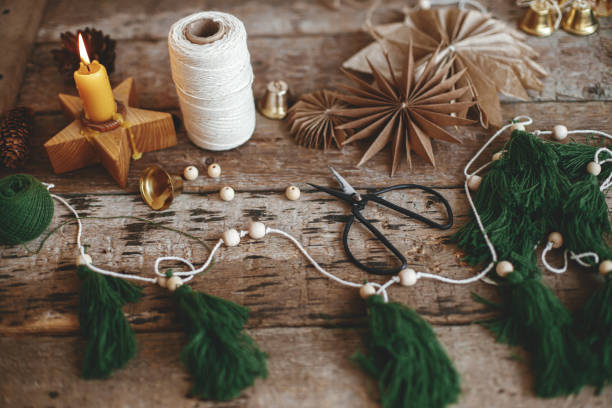 istock Making christmas trees garland. Christmas thread trees, bells, star, candle, scissors on rustic wood 1353652796