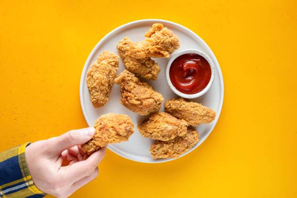 istock Male hand picking fried chicken wing 1353655047