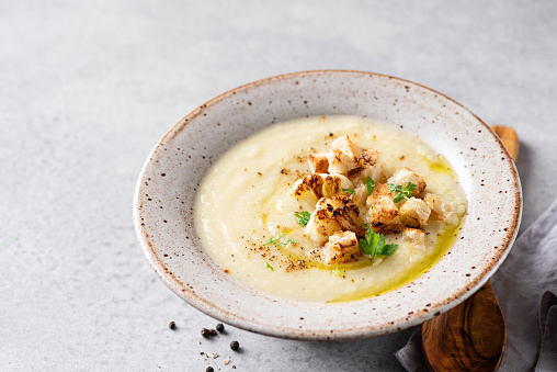 Cauliflower cream soup in bowl served with olive oil and bread croutons. Copy space