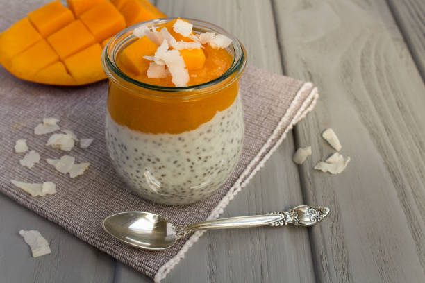 istock Pudding with chia seed, mango and coconut chips in the glass jar on the gray background. Close-up. 1353655142