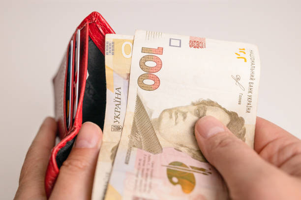 hombre de la mano saca billetes de hryvnia de una billetera roja para pagar servicios, préstamos - ukraine hryvnia currency paper currency fotografías e imágenes de stock