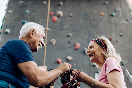 Senior couple trying climbing on the artificial rock and having fun together.