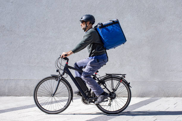 delivery person riding electric bicycle - backpack one mature man only only mature men one man only imagens e fotografias de stock