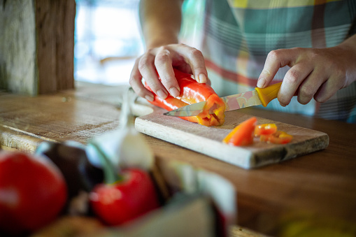 Female hands cutting vegetables on cuttiing board - woman preparing a healthy meal to boost the immune system